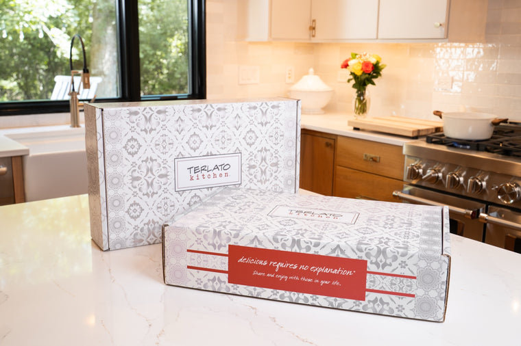 Two closed Terlato Kitchen gift boxes with grey and white patterns on a kitchen counter.