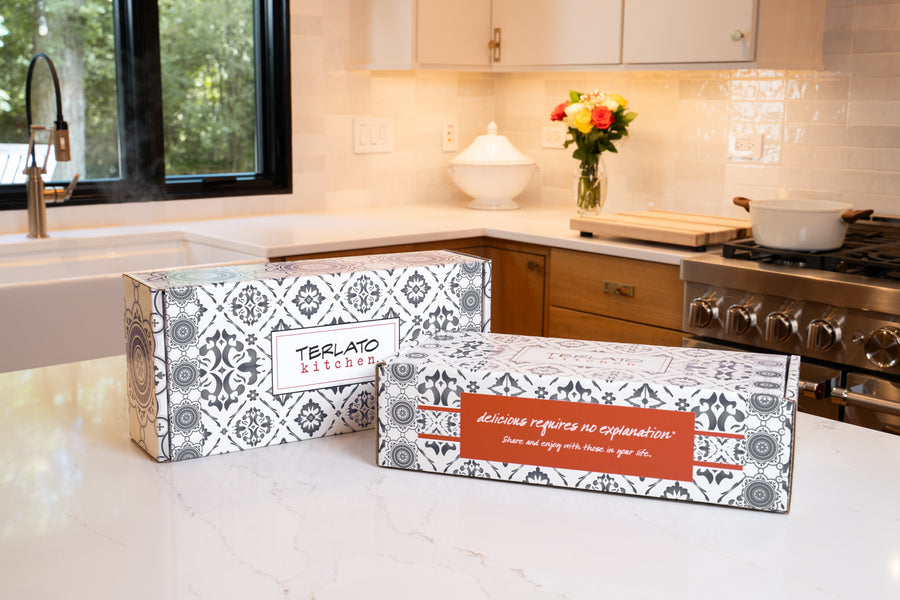 Two closed Terlato Kitchen gift boxes with charcoal and white patterns on a kitchen counter.