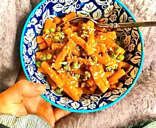 Bowl of spicy vodka rigatoni with sausage, peas and basil
