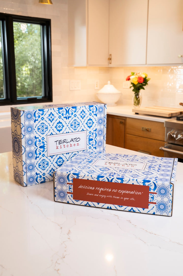 Two closed Terlato Kitchen gift boxes with blue and white patterns on a kitchen counter.