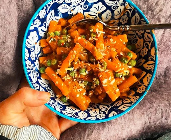 Bowl of spicy vodka rigatoni with sausage, peas and basil